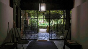 A dimly lit hallway with a wrought iron gate leading to a garden. - Monty Don's secret garden on the Grand Canal (Venezia)