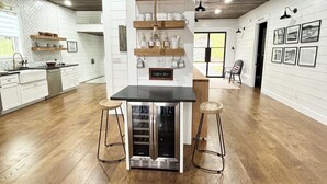 Une cuisine spacieuse dotée d’un îlot central, d’étagères en bois et d’un panneau indiquant l’emplacement du coin café.