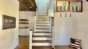 Un escalier en bois menant au deuxième étage, avec un banc et un coussin orné du drapeau américain sur le palier.