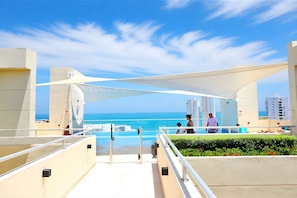 A hotel balcony overlooking a pool with a view of the ocean and adjacent high-rise buildings. - Apartamentos Velas al Mar - by SOHO (Santa Marta)