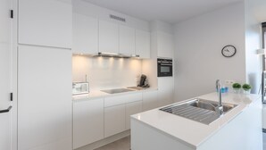 Eine moderne Küche mit weißen Schränken, einer Edelstahlspüle und einem eingebauten Backofen.