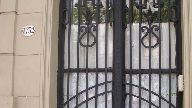 A black wrought iron gate with intricate designs, a white building facade, and a number plate '1752'. - Little Sunny Loft (Buenos Aires)