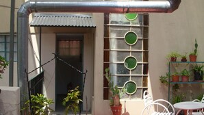A patio with potted plants, a metal chair, and a table. - Little Sunny Loft (Buenos Aires)