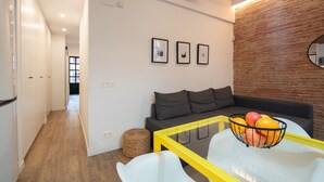 Ein modernes Wohnzimmer mit einer Couch, einem Glastisch mit Obst und einer Wand mit Backsteinverkleidung.