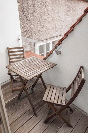 A wooden table and chairs on a balcony with a textured wall and a window. - Luxury urban apartment in the heart of Graz's Old Town (Graz)