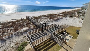 A beach view from a balcony with a wooden deck and a covered seating area. - Beachfront Condo • Rooftop Pool • Sleeps 8 (Mexico Beach)