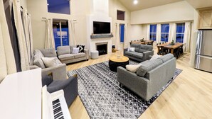 Amplia sala de estar con chimenea, sofás, una mesa de centro y televisor.