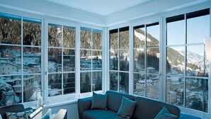 A cozy room with a large window offering a snowy mountain view. - Penthouse in Bad Gastein Near Ski Lifts (Bad Gastein)