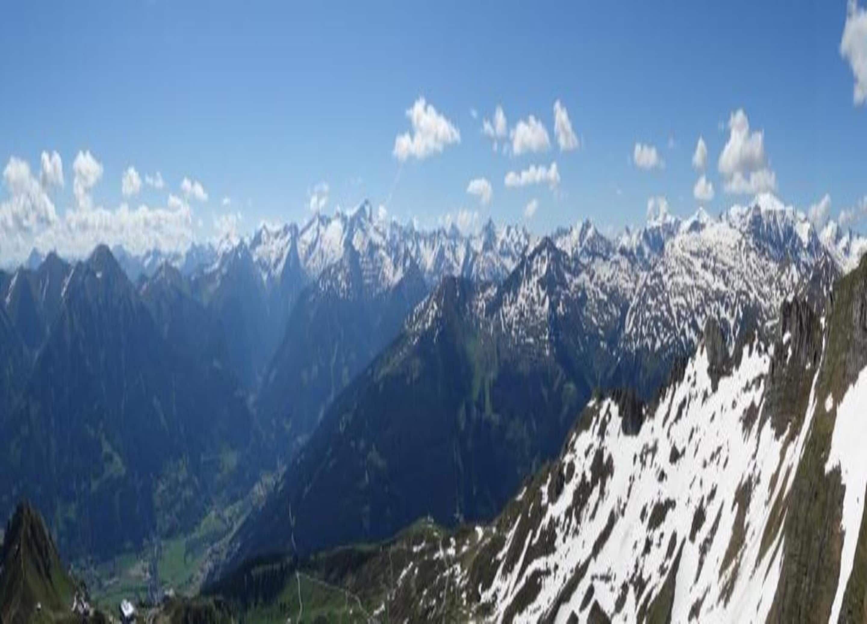 Eine Berglandschaft mit schneebedeckten Gipfeln und blauem Himmel.