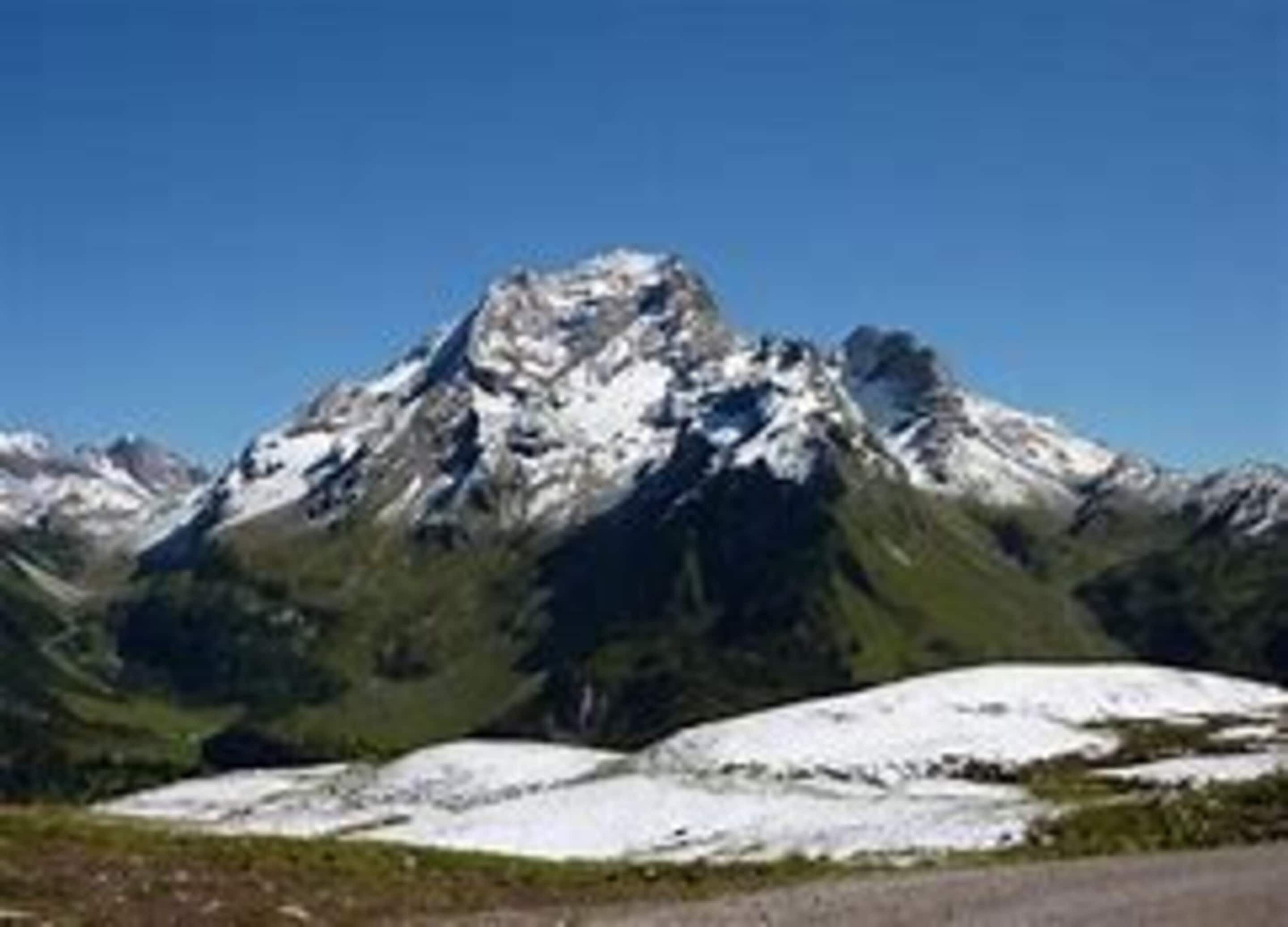 A mountain with snow-capped peaks and a clear blue sky.