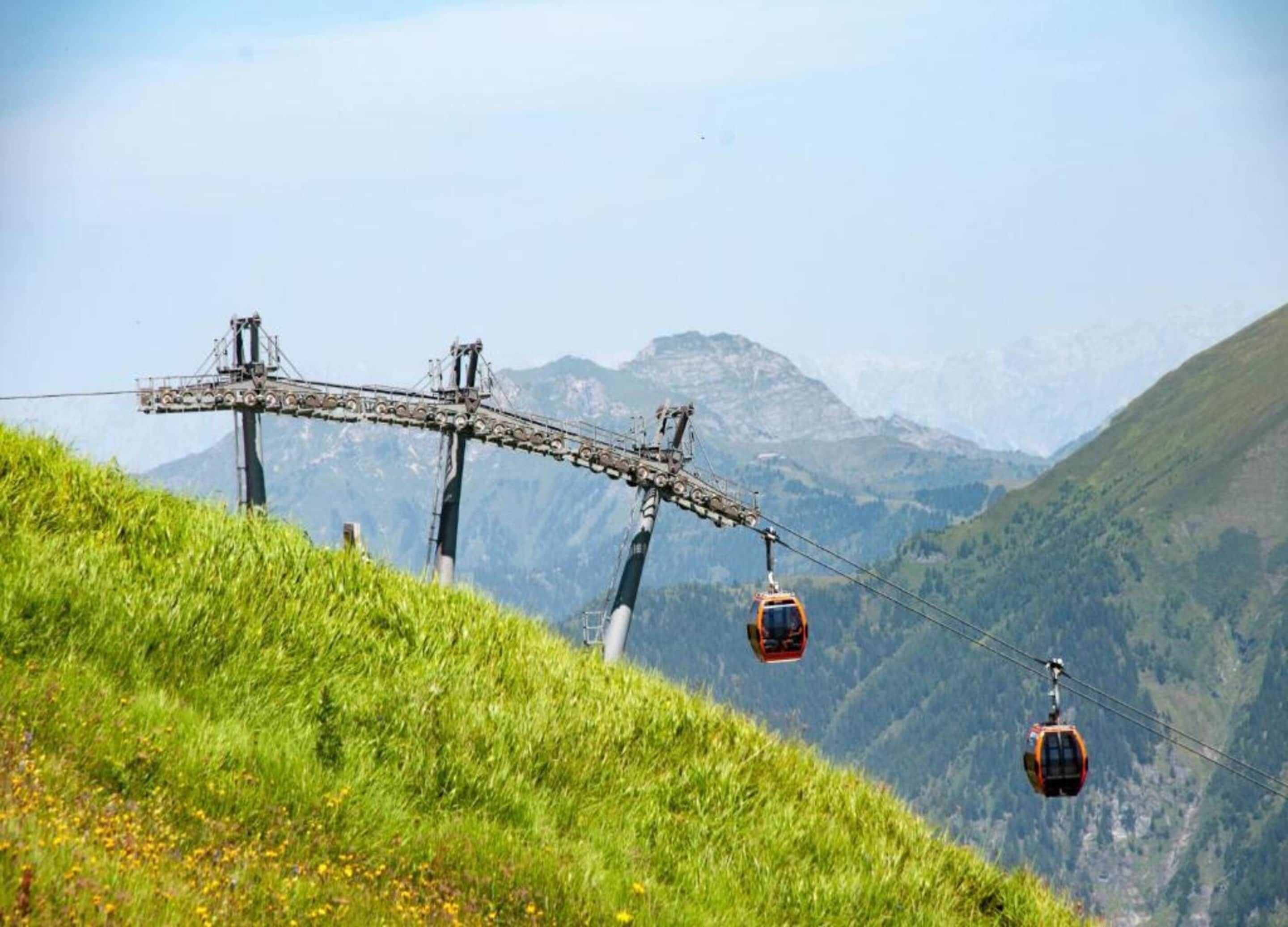 Sistema de teleférico con dos cabinas sobre una cresta montañosa.
