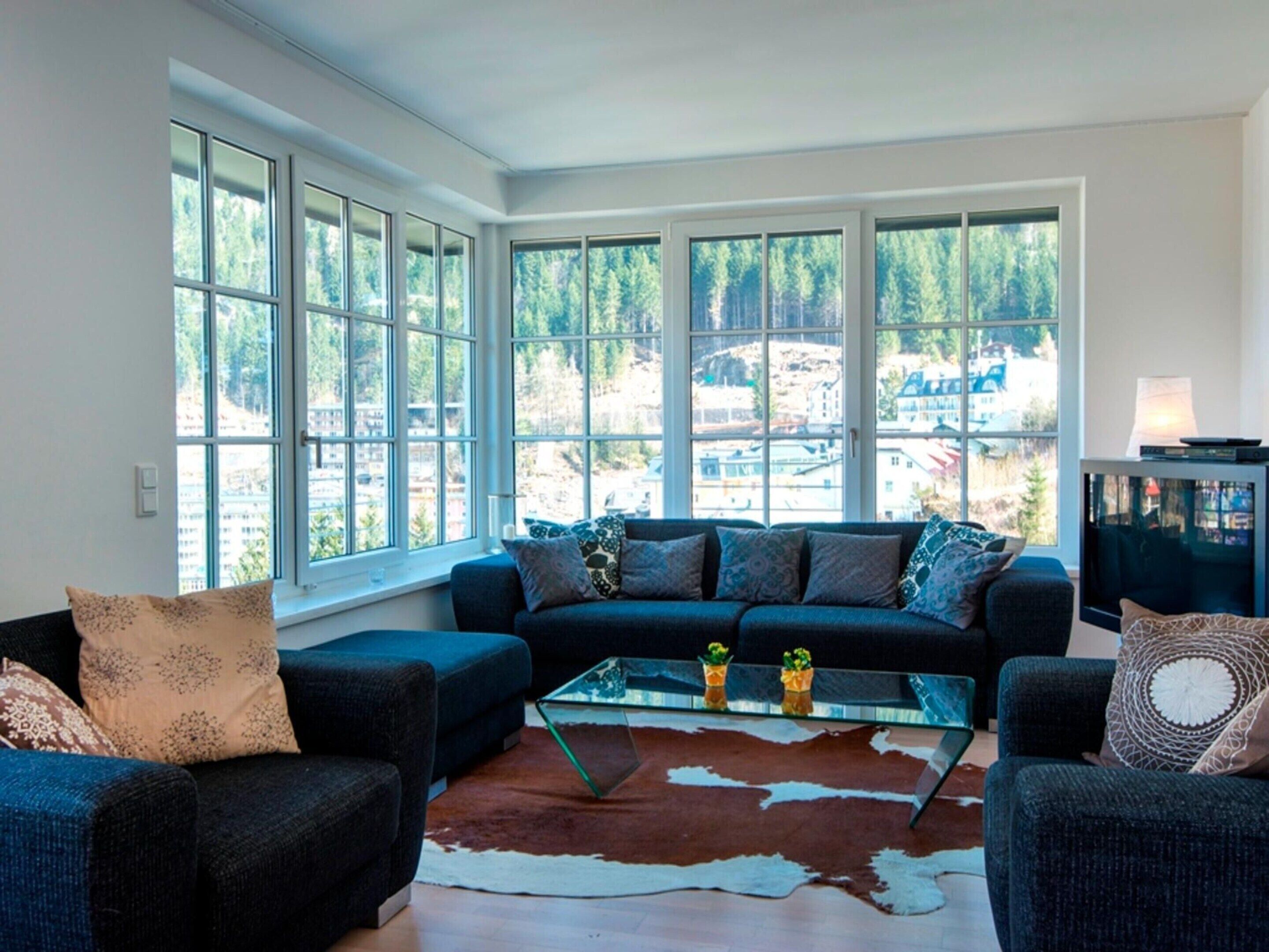 A living room with a sofa set, a glass coffee table, and a cowhide rug.