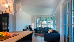 A modern living room with a wooden table, a sofa, and a TV. - Penthouse in Bad Gastein Near Ski Lifts (Bad Gastein)