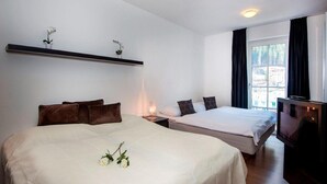 A hotel room with two beds, a TV, a bedside table with a lamp, and a window with curtains. - Penthouse in Bad Gastein Near Ski Lifts (Bad Gastein)