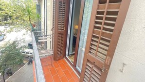 Ein Balkon mit Blick auf eine Straße, ein abgestelltes Motorrad und ein Gebäude mit Balkonbrüstung.