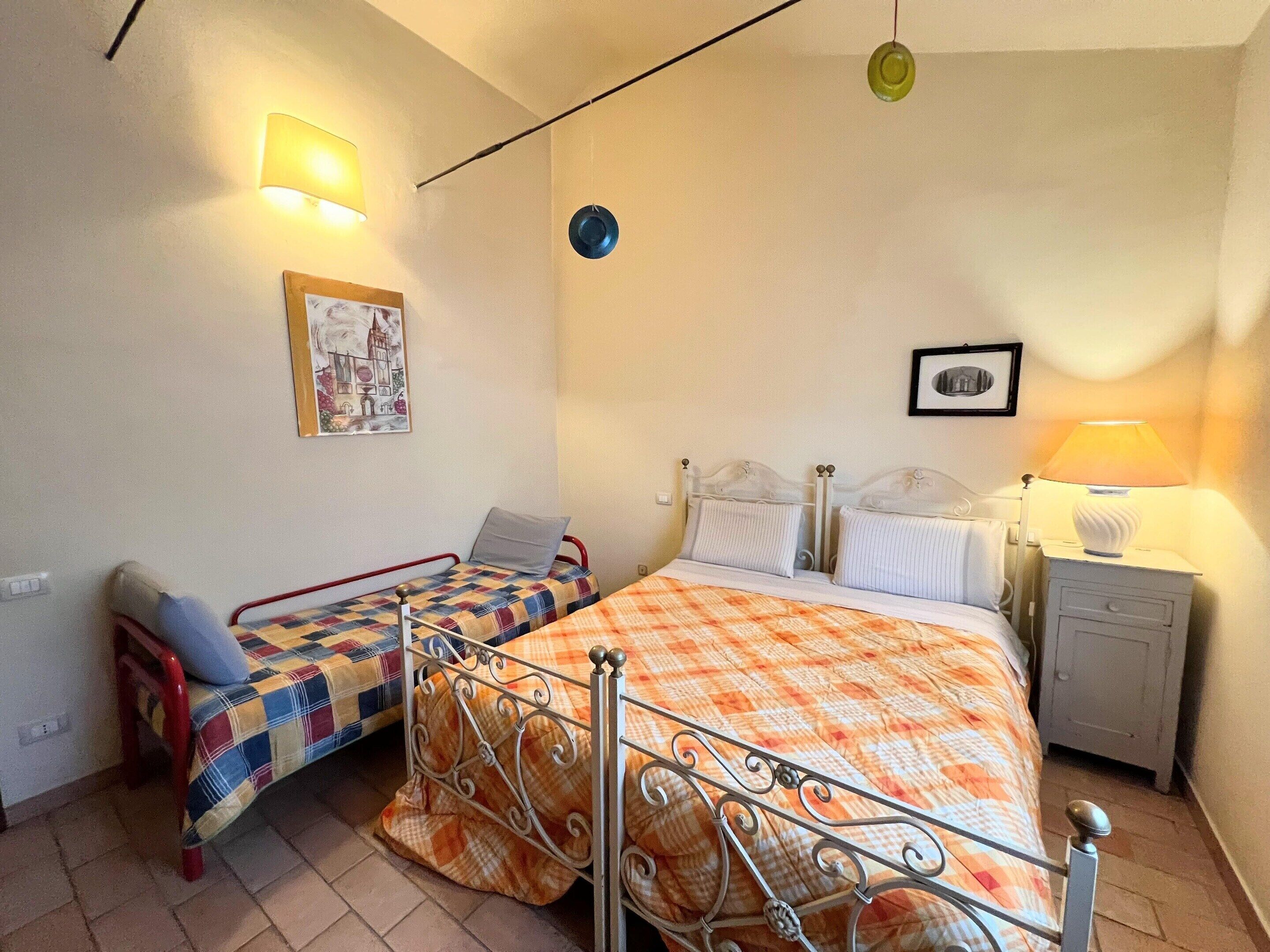 A bedroom with two beds, a nightstand, a lamp, and wall-mounted lights.