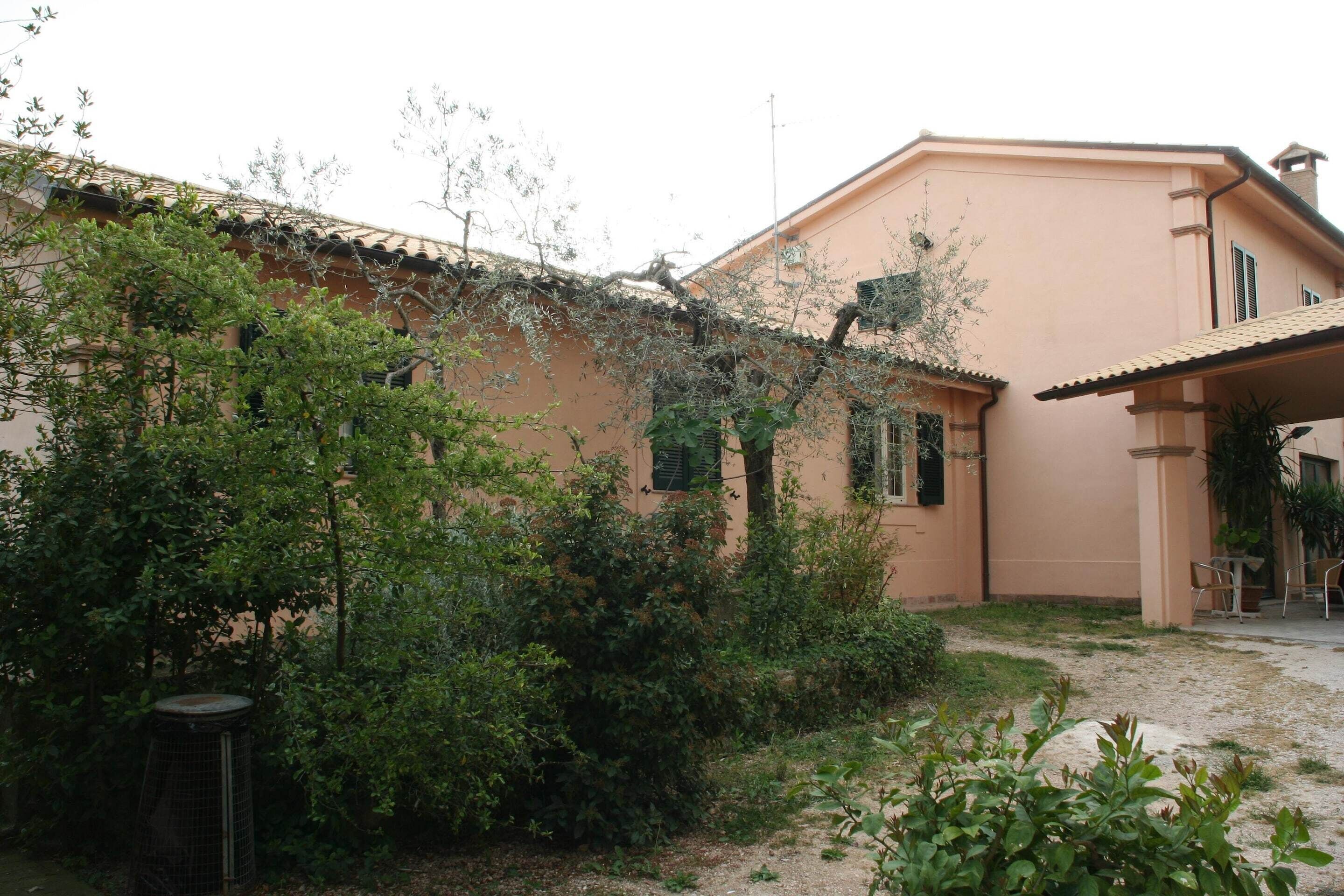 Ein Gebäude mit Ziegeldach, überdachter Terrasse und umgebender Bepflanzung.