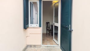 Ein schmaler Eingang mit einer Tür und einem Fenster mit Rollläden.
