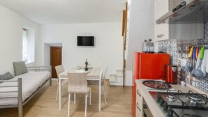 Un espace de vie compact comprenant un coin cuisine, un coin repas et un lit.