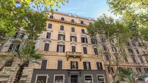 Un edificio a più piani con uno stile architettonico classico, caratterizzato da un ingresso centrale con insegna, numerose finestre e balconi.