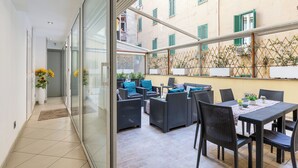 Un moderno appartamento con una porta vetrata che dà su un balcone. Il balcone presenta mobili in vimini e un tavolo da pranzo.