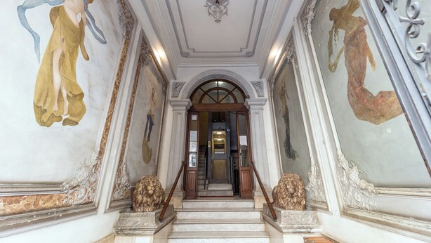 Un'imponente scalinata con affreschi elaborati e un soffitto decorativo.