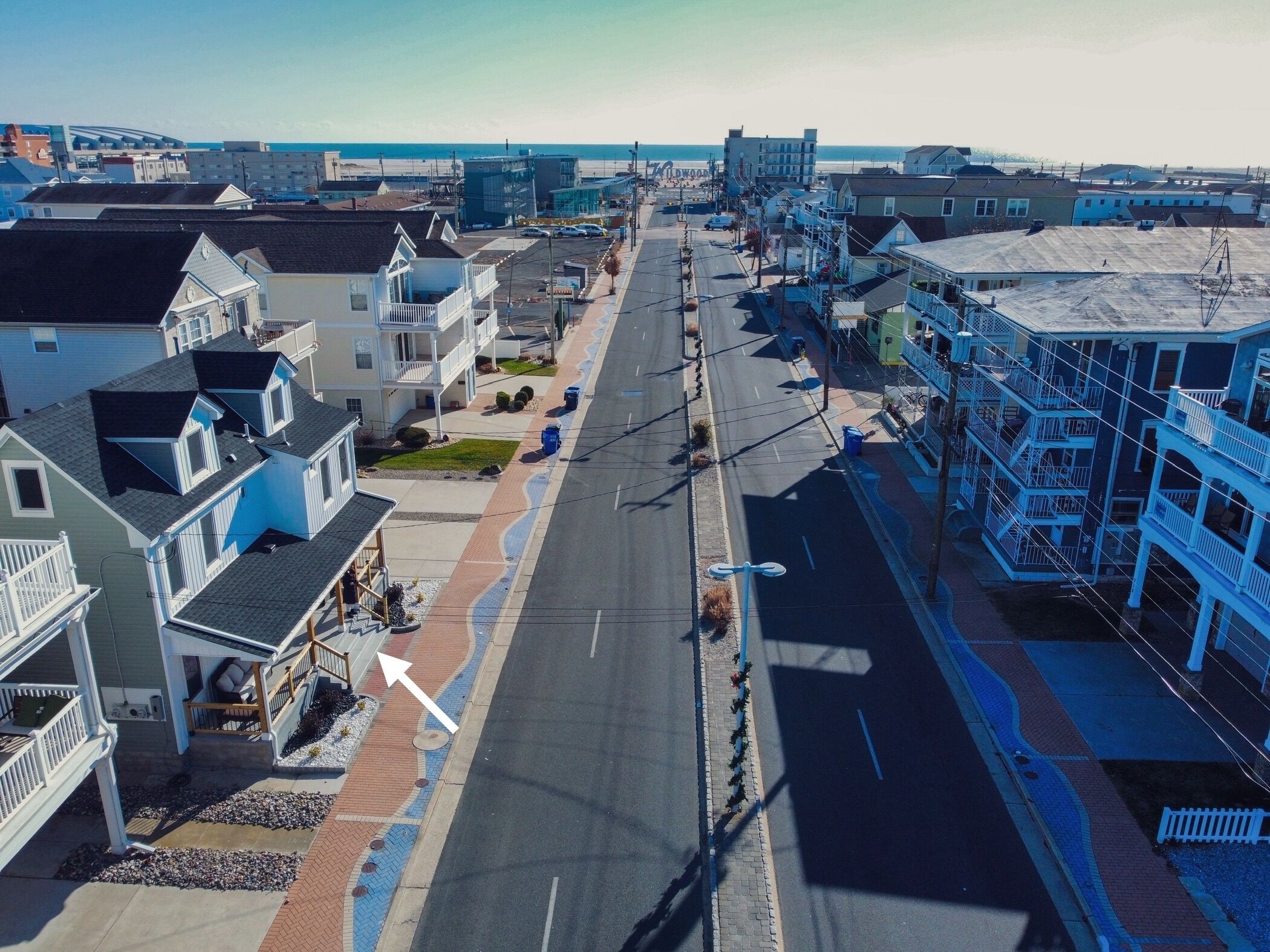 A coastal street with multi-story buildings, including a hotel with balconies and a view of the beach.