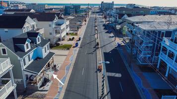 A coastal street with multi-story buildings, including a hotel with balconies and a view of the beach.