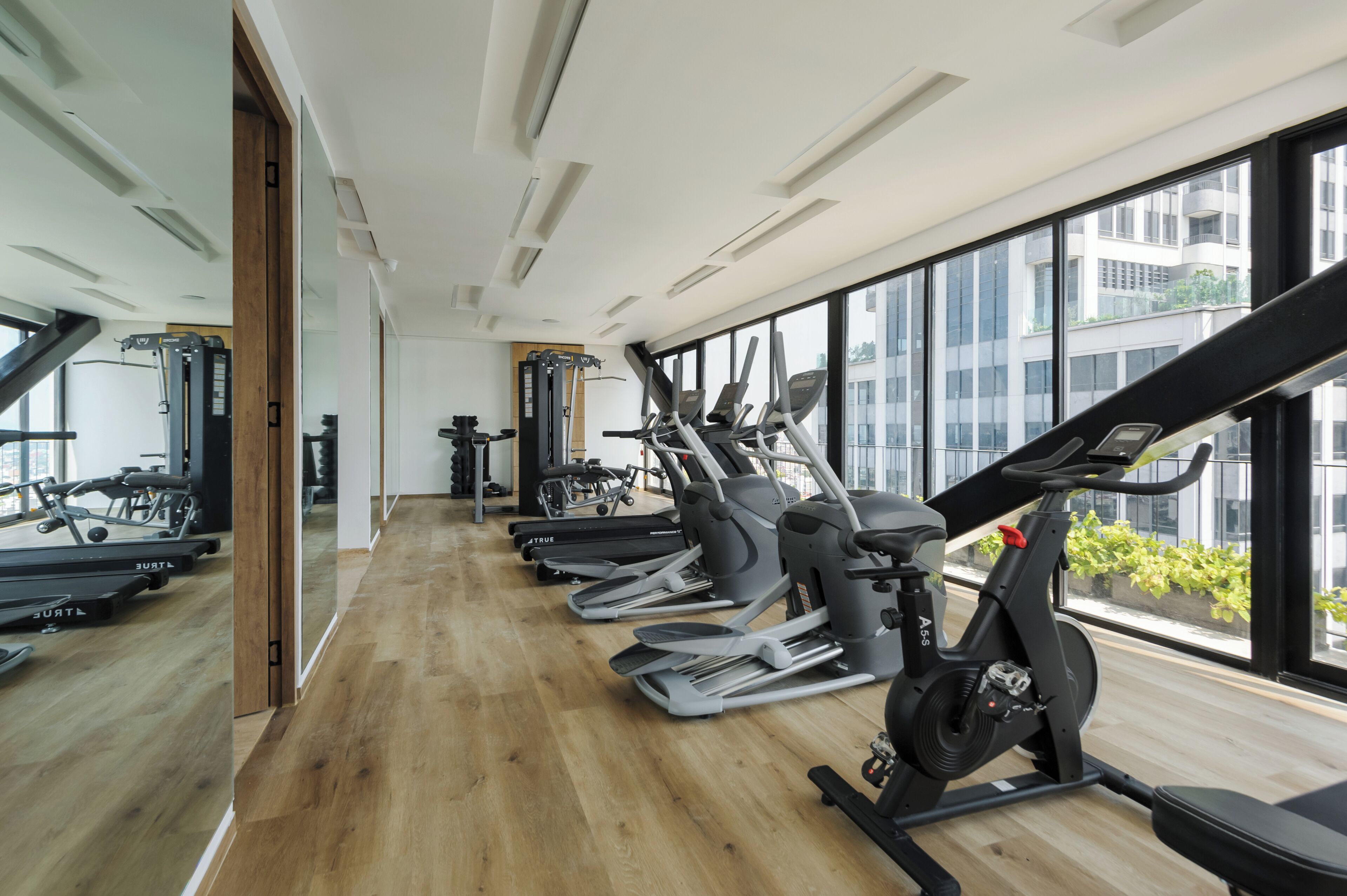 Une salle de sport équipée de matériel d’exercice, dotée de grandes fenêtres et d’un plancher en bois.