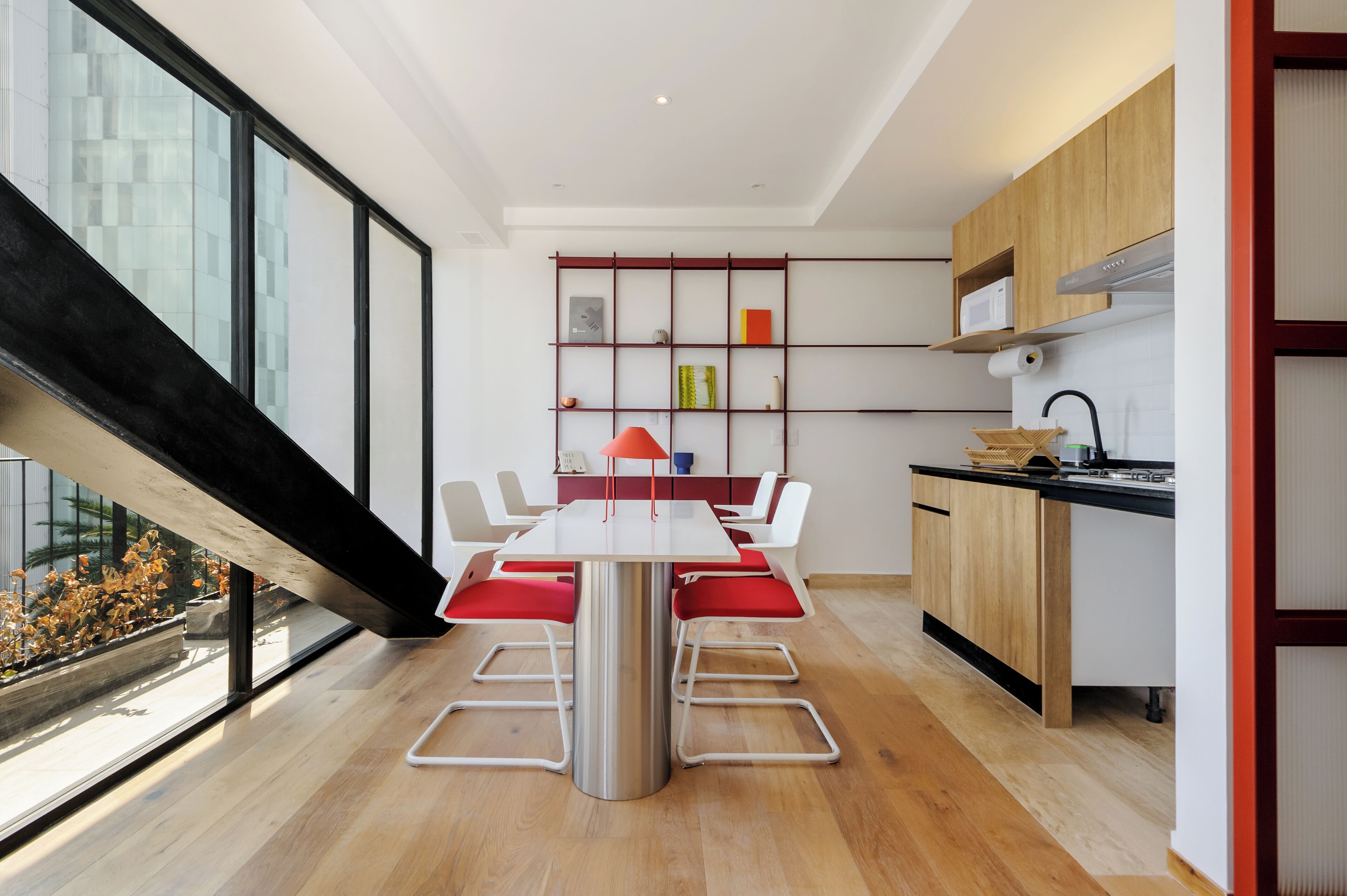 A modern kitchen with a dining area, large windows, and a staircase.