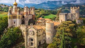 Un castillo con múltiples torres y un amplio patio rodeado de abundante vegetación.