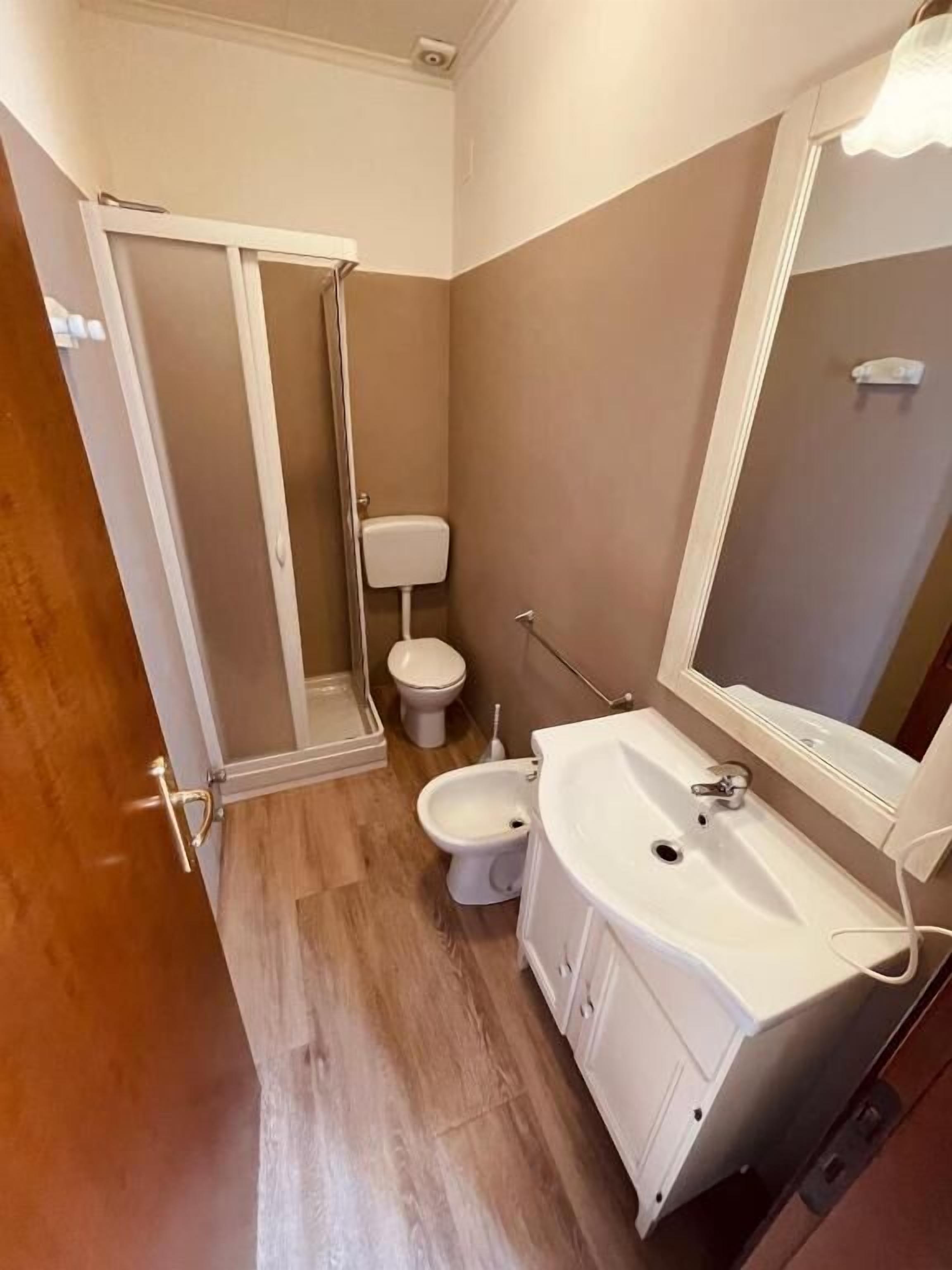 Une salle de bain compacte comprenant une douche, des toilettes, un bidet et un lavabo.
