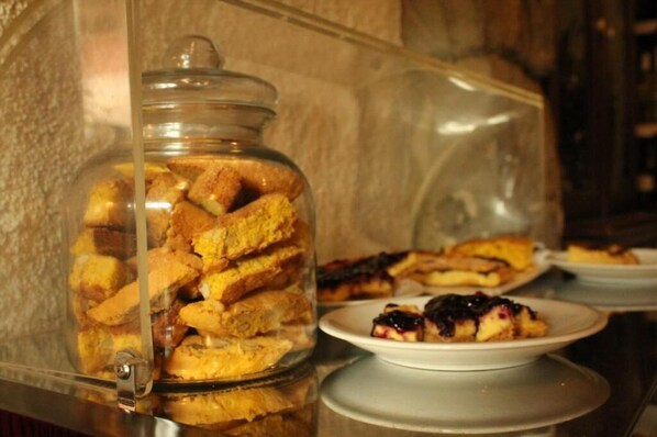 A glass display case filled with various pastries and a plate with a dessert on a table.