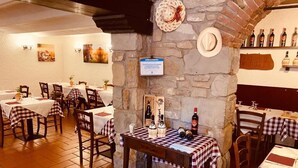 Un restaurante con manteles a cuadros, paredes de piedra y una variedad de botellas en las estanterías.