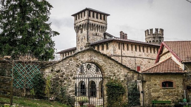 Un edificio histórico de piedra con una torre y ventanas de arco.