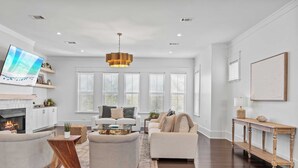 A spacious living room with a fireplace, two sofas, a coffee table, and a large TV.