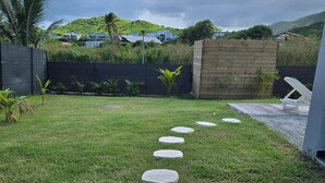 A pathway of stepping stones leading to a wooden fence and a white chair.
