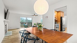 A modern kitchen with stainless steel appliances, a dining area with a wooden table and chairs, and a balcony with a view of the outdoors. - Charming 3 BD Retreat - Spa, EV Charger, Views (Santa Rosa)