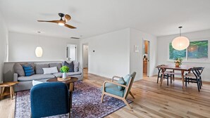 A modern living room with a sofa, coffee table, and chairs, a dining area with a table and chairs, and a ceiling fan. - Charming 3 BD Retreat - Spa, EV Charger, Views (Santa Rosa)