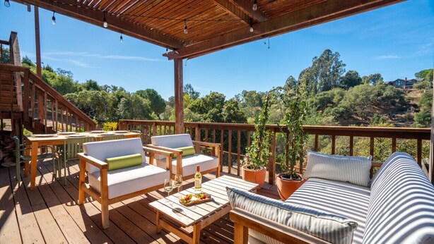 A wooden deck with outdoor furniture, including a sofa and chairs, and a dining table. - Charming 3 BD Retreat - Spa, EV Charger, Views (Santa Rosa)
