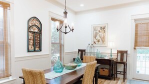 A dining room with a wooden table, wicker chairs, and decorative vases. - 5 Mins to Beach, Shared Pool, Covered Deck, Bikes Heron Cottage by Avantstay (Santa Rosa Beach)