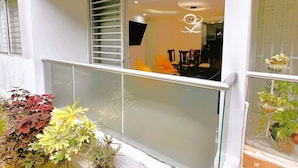Uma varanda com porta de vidro, plantas em vasos e uma área de refeições visível através da porta.