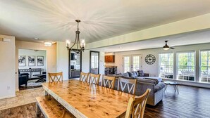 Un vaste espace de vie comprenant une grande table à manger en bois, un canapé et un lustre.