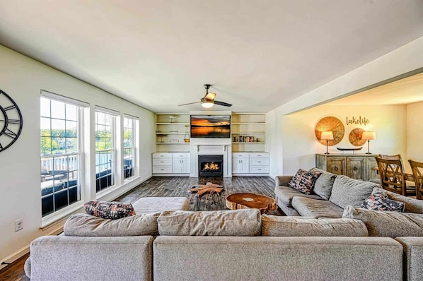 A living room with a fireplace, a sofa, a coffee table, and a bookshelf. - Lake Anna Lakefront | Hot Tub, Boat Dock, Beach (Mineral)