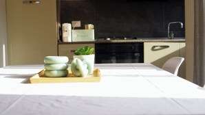 Eine moderne Küche mit klarem Design, mit einem Holztablett, Kerzen und einem Topf mit Pflanze auf dem Tisch.