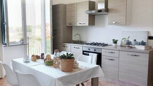 A modern kitchen with a dining table set for two, a stove, and cabinets. - Quick Home Mimosa - One Bedroom Apartment, Sleeps 4 (Alice Castello)