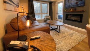 Ein modernes Wohnzimmer mit Ledersofa, rundem Couchtisch und Kamin.