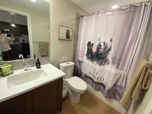 A bathroom with a white sink, a toilet, and a shower curtain with a bear design.