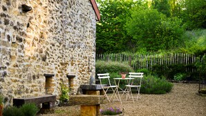 A rustic stone building with outdoor seating, a gravel path, and a wooden fence. - Le Point du Jour, a charming house (SAPOGNE SUR MARCHE)