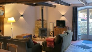 A cozy living room with a fireplace, a television, and a dining area. - Le Point du Jour, a charming house (SAPOGNE SUR MARCHE)